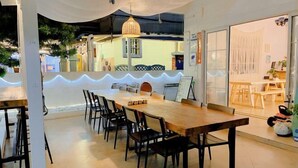A dining area with a long wooden table and black chairs, a hanging light fixture, and a view of the outside. - Shenzhen Xiyong Sanke Xiaoshu Homestay (Shenzhen)