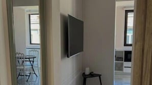 A hallway with a large mirror, a mounted television, and a small table. - Luxurious Central Baku Apartment (Baku)