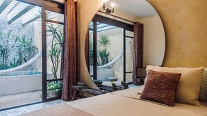A bedroom with a large bed, a view of a garden through a glass door, and a hammock outside. - Itinerante- Casa Santa Ana, Mérida Centro (Mérida)