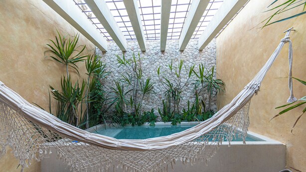 A hammock over a pool with plants and a stone wall. - Itinerante- Casa Santa Ana, Mérida Centro (Mérida)