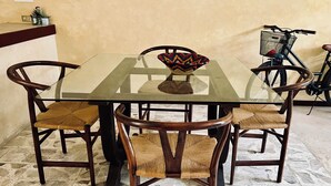 A round glass table with six wooden chairs, a decorative bowl, and a bicycle in the background. - Itinerante- Casa Santa Ana, Mérida Centro (Mérida)