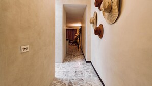 A hallway with a stone floor, a door with a lock, and a wall with three hats. - Itinerante- Casa Santa Ana, Mérida Centro (Mérida)