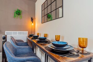 Enjoy meals in this stylish dining area with a long table, comfortable chairs, and a potted plant.