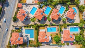 Un quartier résidentiel composé de plusieurs maisons, chacune dotée d’une piscine et d’un toit recouvert de tuiles.
