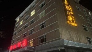 Un immeuble à plusieurs étages, doté d’une enseigne et de fenêtres illuminées.