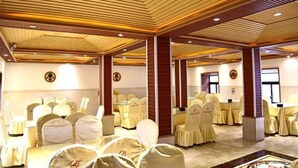 A conference room with rows of chairs, a wooden ceiling, and a carpeted floor. - Scenic Natural Hotel (Daocheng County)