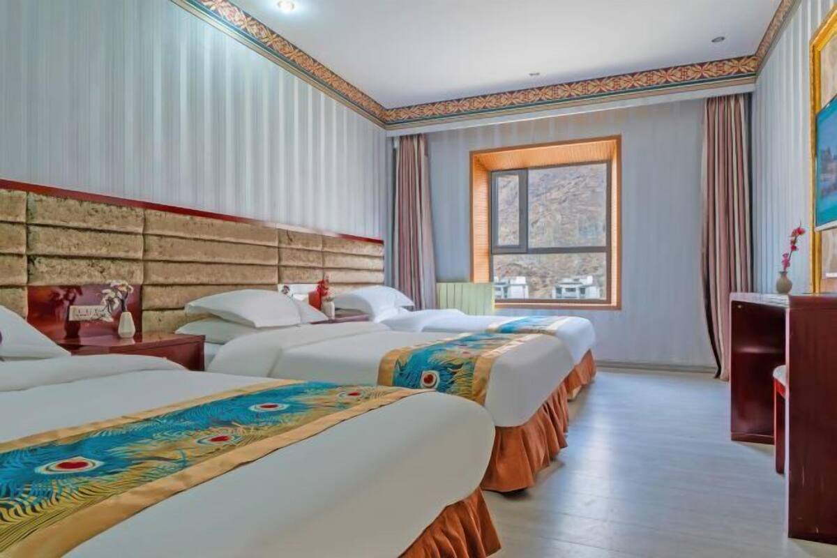Habitación de hotel con dos camas, un ventanal grande y vistas al exterior.