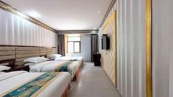 A hotel room with three beds aligned along one wall, a television mounted on the wall, and a window providing natural light.