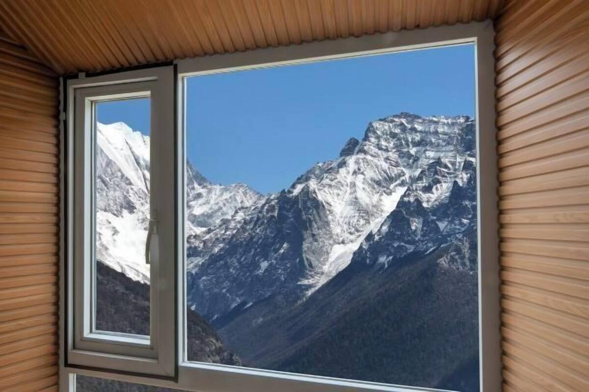 Una habitación con un amplio ventanal que ofrece vistas a una cordillera nevada.