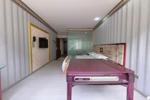 Habitación de hotel con cama, mesita de noche, teléfono y ventana con persianas.