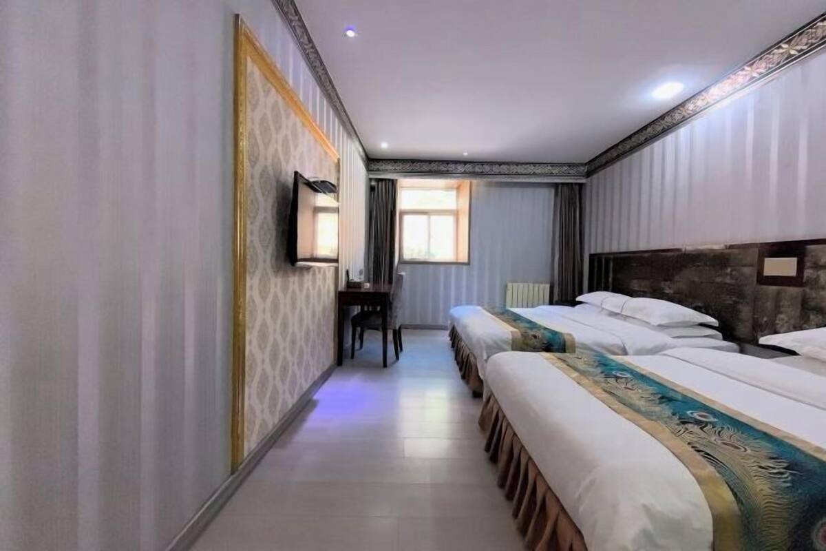 Una habitación de hotel con dos camas, un escritorio y una ventana.