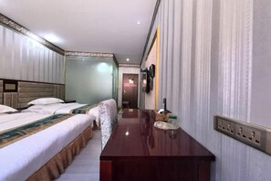 Una habitación de hotel con una cama, un escritorio de madera, un teléfono y un enchufe de pared.