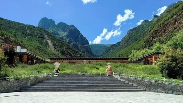 A set of stone steps leading up to traditional wooden buildings with a mountainous backdrop. - Scenic Natural Hotel (Daocheng County)