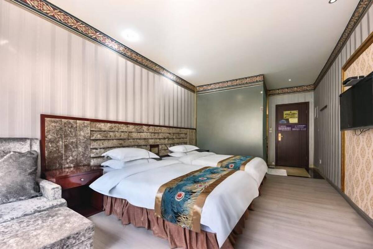 Una habitación de hotel con una cama grande, cabecera de madera, un banco de piedra y un televisor en la pared.