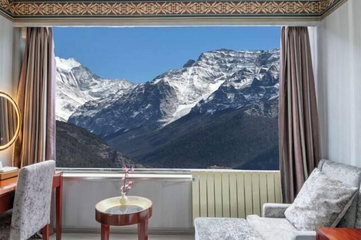 Una habitación con un ventanal que ofrece vistas a montañas nevadas.