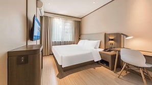 Une chambre d’hôtel avec un grand lit, un bureau avec une chaise, une télévision et une table de chevet avec une lampe.
