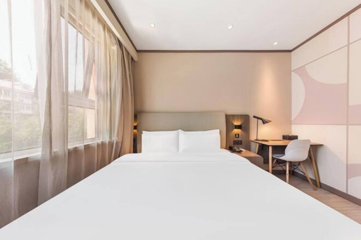 A modern hotel room with a large bed, a desk, and a chair.