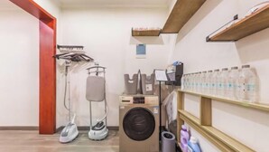 Un espace buanderie équipé d’un lave-linge, d’un sèche-linge, d’un fer à repasser et d’une planche à repasser.