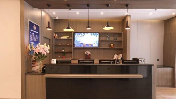 Un comptoir d’accueil doté d’un téléviseur à écran plat, de luminaires suspendus et d’un vase rempli de fleurs.