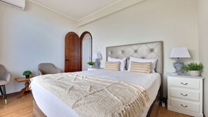 Une chambre à coucher avec un grand lit, une table de chevet avec une lampe, une chaise et une armoire.