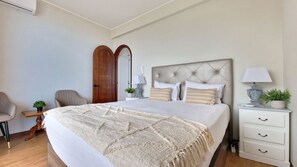 Ein Schlafzimmer mit einem großen Bett, einem Nachttisch mit Lampe, einem Sessel und einem Kleiderschrank.