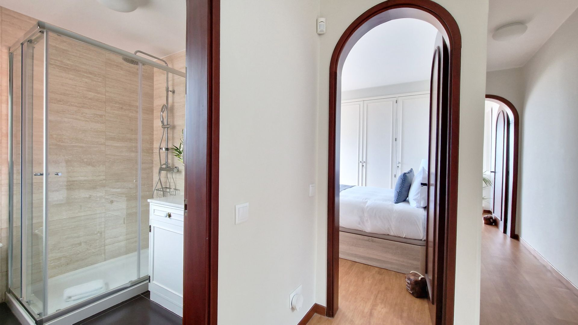 Et moderne badeværelse med glasvæg omkring bruseniche og et hvidt toiletbord.