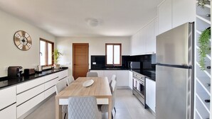 Une cuisine moderne avec une table à manger en bois, des armoires blanches et des appareils électroménagers en acier inoxydable.
