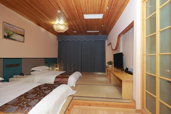 A hotel room with two beds, a wooden ceiling, a large window, and a television.