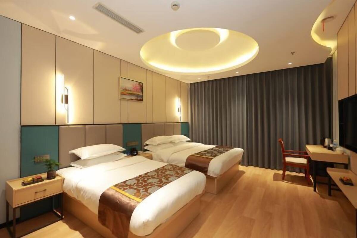Une chambre d’hôtel avec deux lits, un bureau, une chaise et un téléviseur.