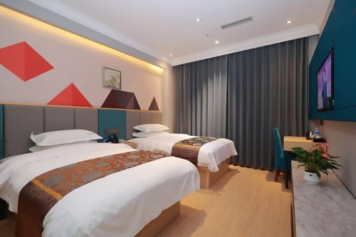 Une chambre d’hôtel avec deux lits, une télévision, un bureau et une plante en pot.
