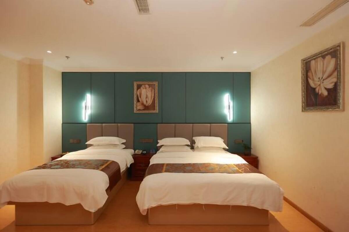 Une chambre d’hôtel avec deux lits, des murs de couleur turquoise et une œuvre d’art encadrée au-dessus des lits.
