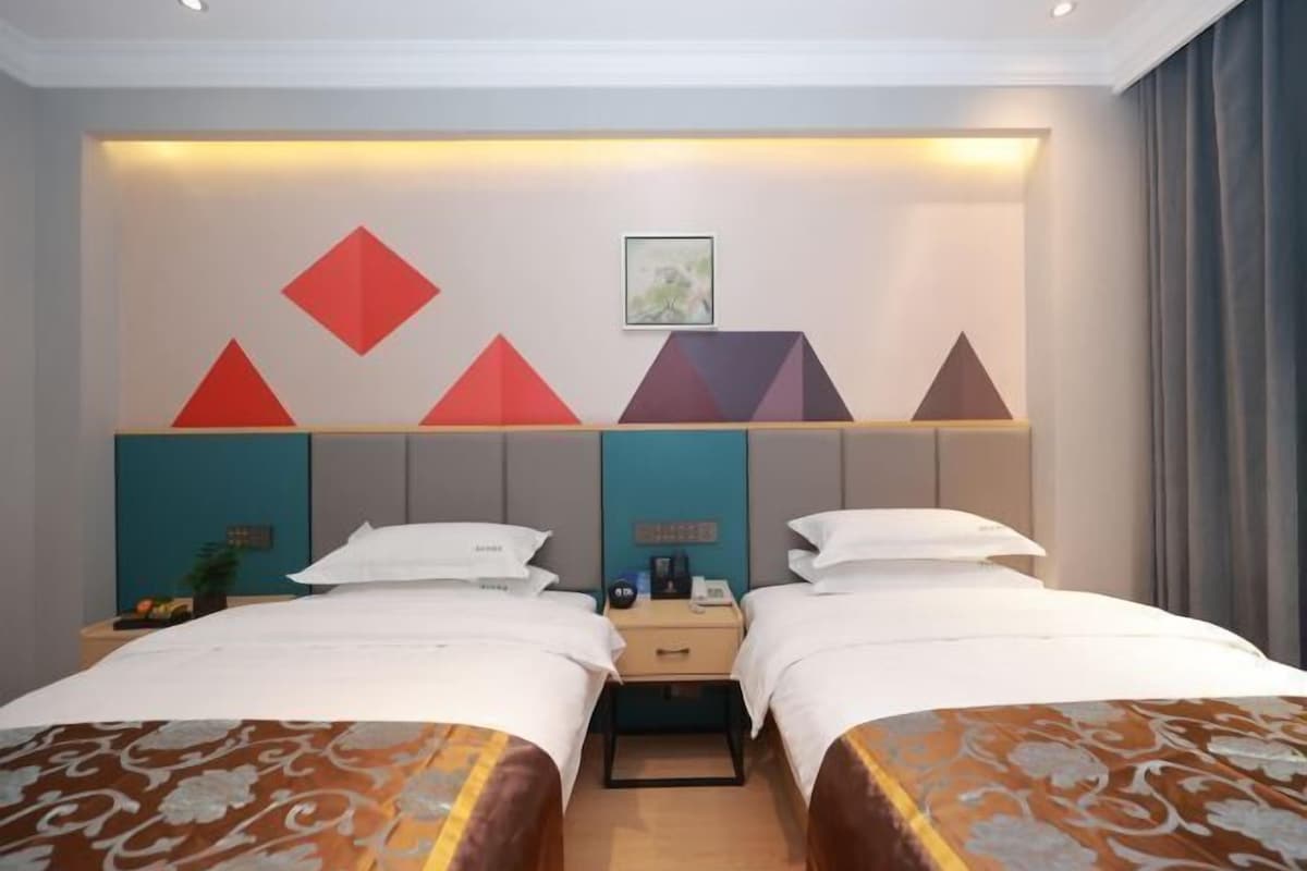 A hotel room with two beds, a nightstand, and a wall-mounted shelf with geometric decorations.