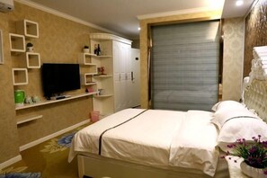 Ein Schlafzimmer mit einem Bett, einem Fernseher, Regalen mit Gegenständen und einem Kleiderschrank.