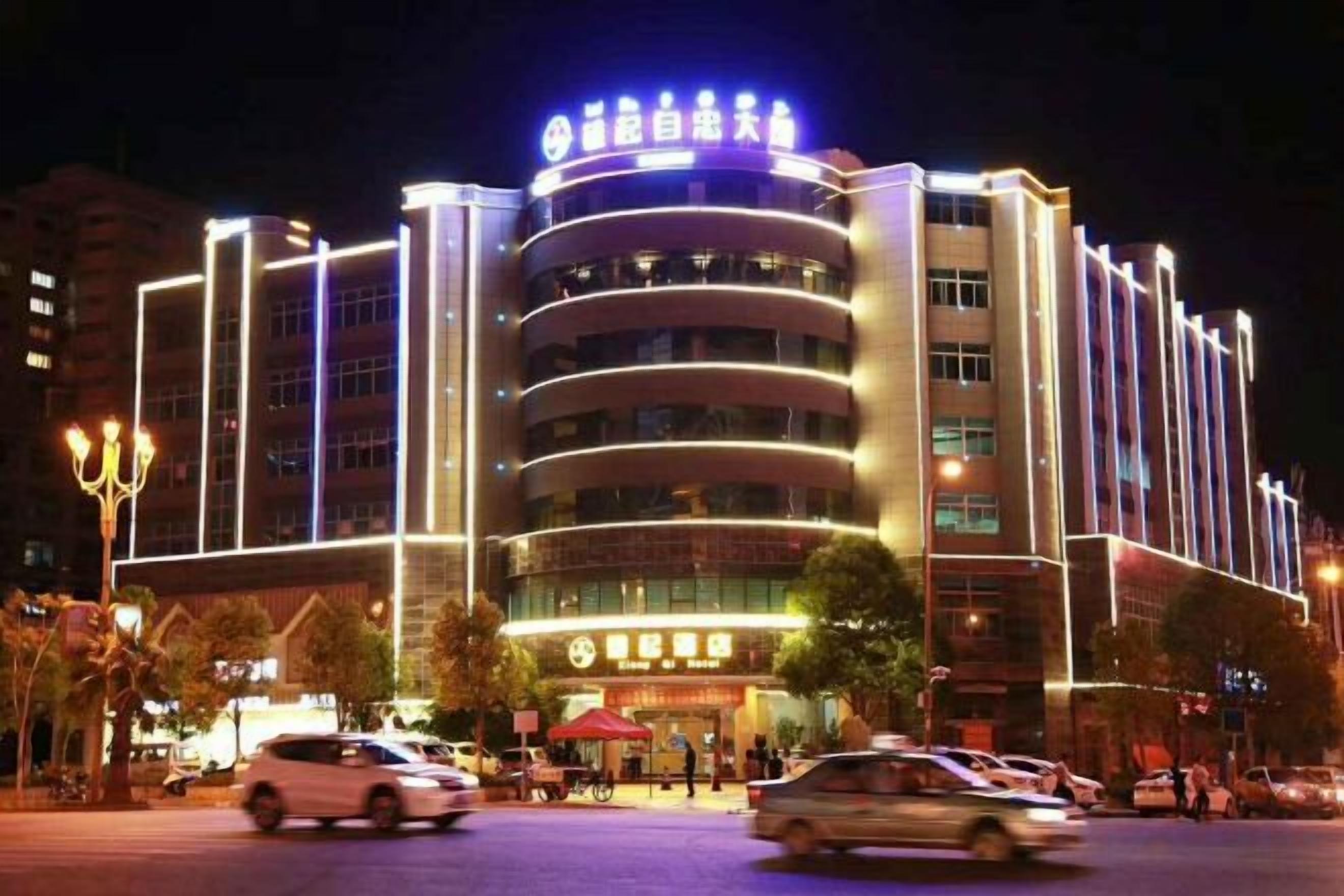 Un hotel de varios pisos con un letrero llamativo en la parte superior, múltiples plantas y fachada bien iluminada.