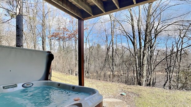 A hot tub with a wooden deck and a view of a wooded area. - Deep Creek Village #33 by Taylor Made Deep Creek (McHenry)