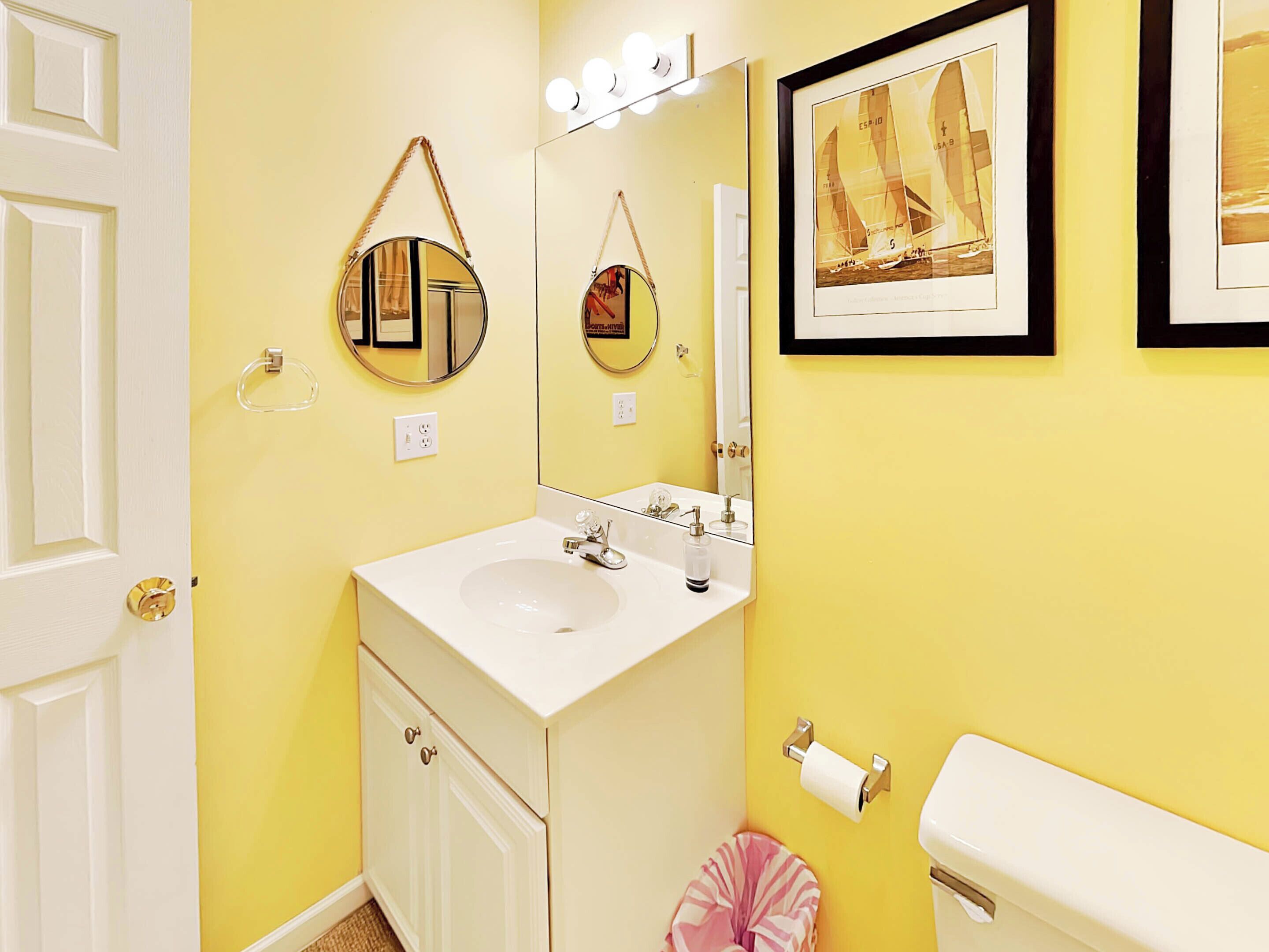 Un bagno con un lavandino bianco, uno specchio, un quadro incorniciato e un water.