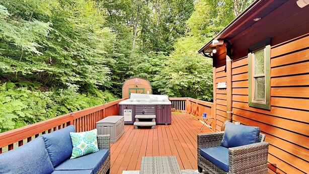 A deck with outdoor furniture, a hot tub, and a wooden cabin in the background. - Hillside Hideaway by Taylor Made Deep Creek (McHenry)