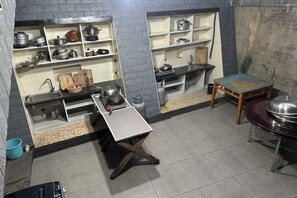 A compact kitchen with shelves, a sink, and a table. - Yichun Yushuxia Hotel (Yichun)