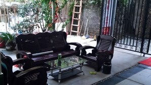 Eine Terrasse mit einer schwarzen Couch, einem Glastisch und einem Sessel.