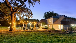 Een huis met een achtertuin, terras, boom en lichtjes.