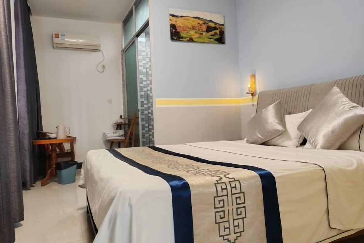 A neatly made bed with a decorative headboard, a bedside table with a lamp, and a painting on the wall.