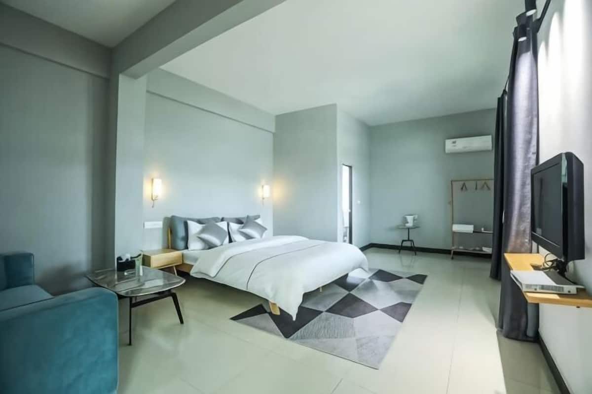 A modern hotel room with a bed, a desk, a chair, and a television.