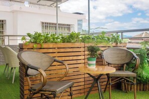 A patio with wicker chairs and a round table, surrounded by a wooden fence and potted plants. - Shihe Yuanfang Homestay (Renhua)