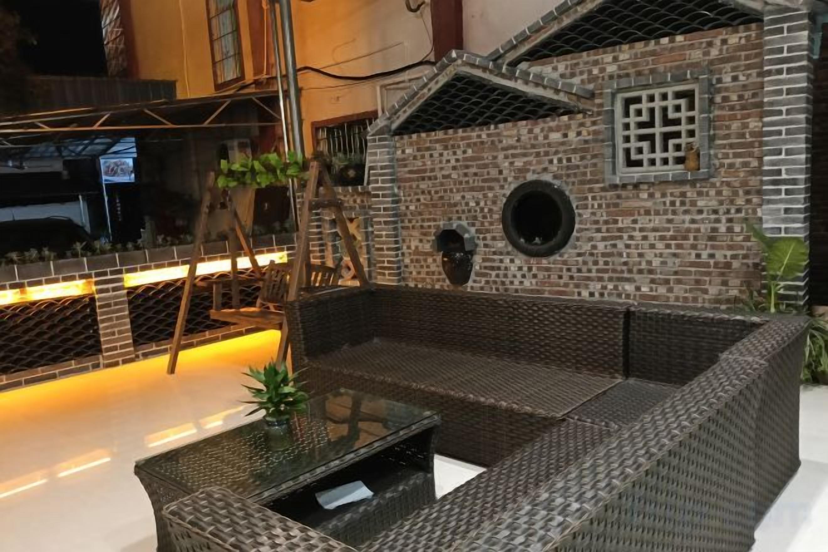 A wicker sofa with a glass table in an indoor setting with brick walls and a decorative wall feature.