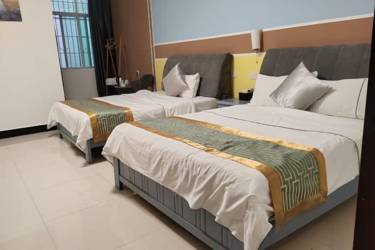 Two single beds with headboards, a bedside table, a nightstand, and a window with curtains.