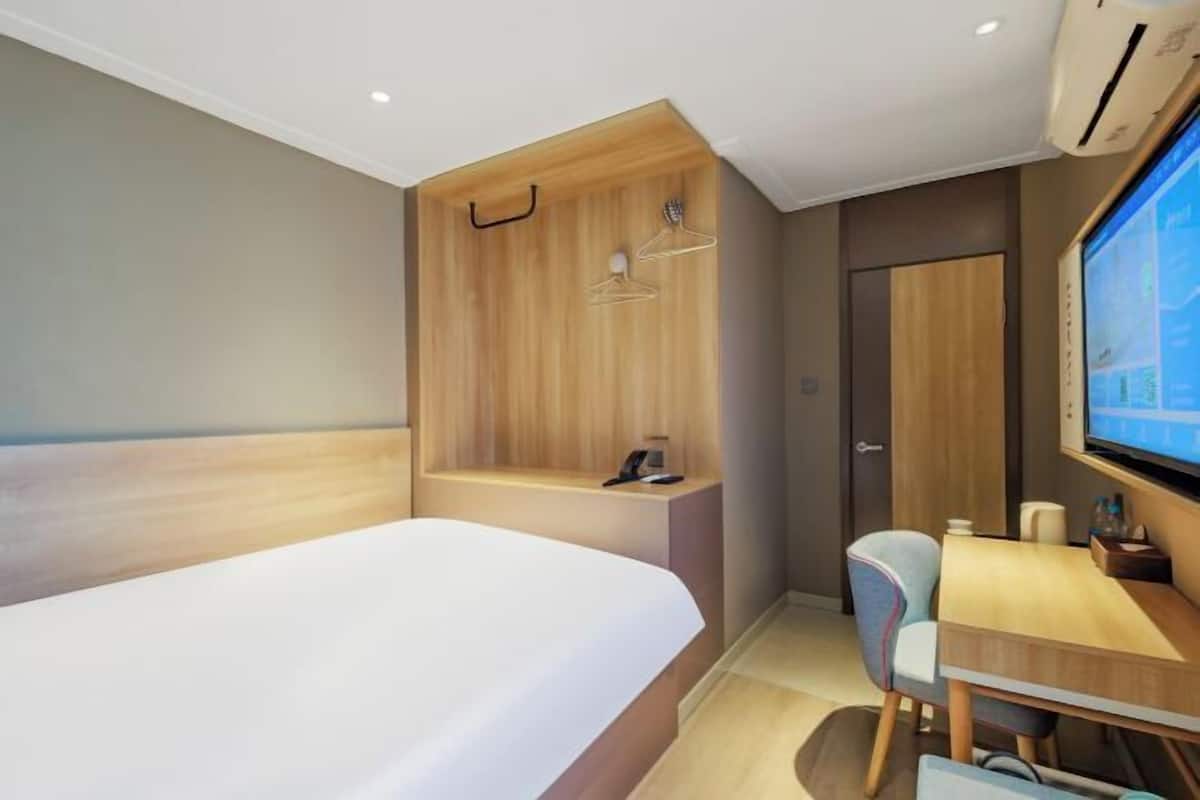 Une chambre d’hôtel équipée d’un lit, d’un bureau, d’une chaise, d’une télévision et d’une armoire.