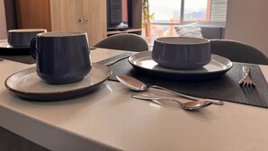 Mesa de comedor dispuesta con dos tazones azul oscuro, una cuchara y un tenedor sobre una base negra.