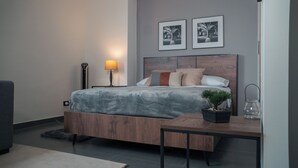 Un dormitorio moderno con una cama de madera, una mesita de noche, una lámpara y dos cuadros enmarcados en la pared.