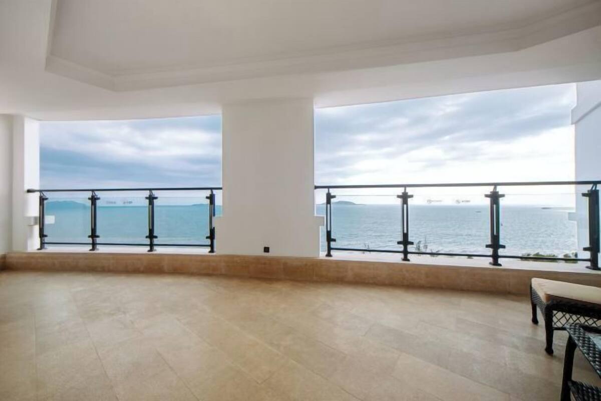 A spacious balcony with a view of the sea and a distant island.