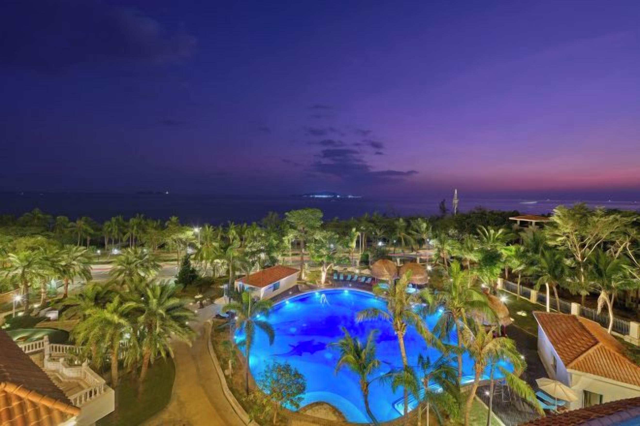 A resort with a swimming pool surrounded by palm trees and buildings.